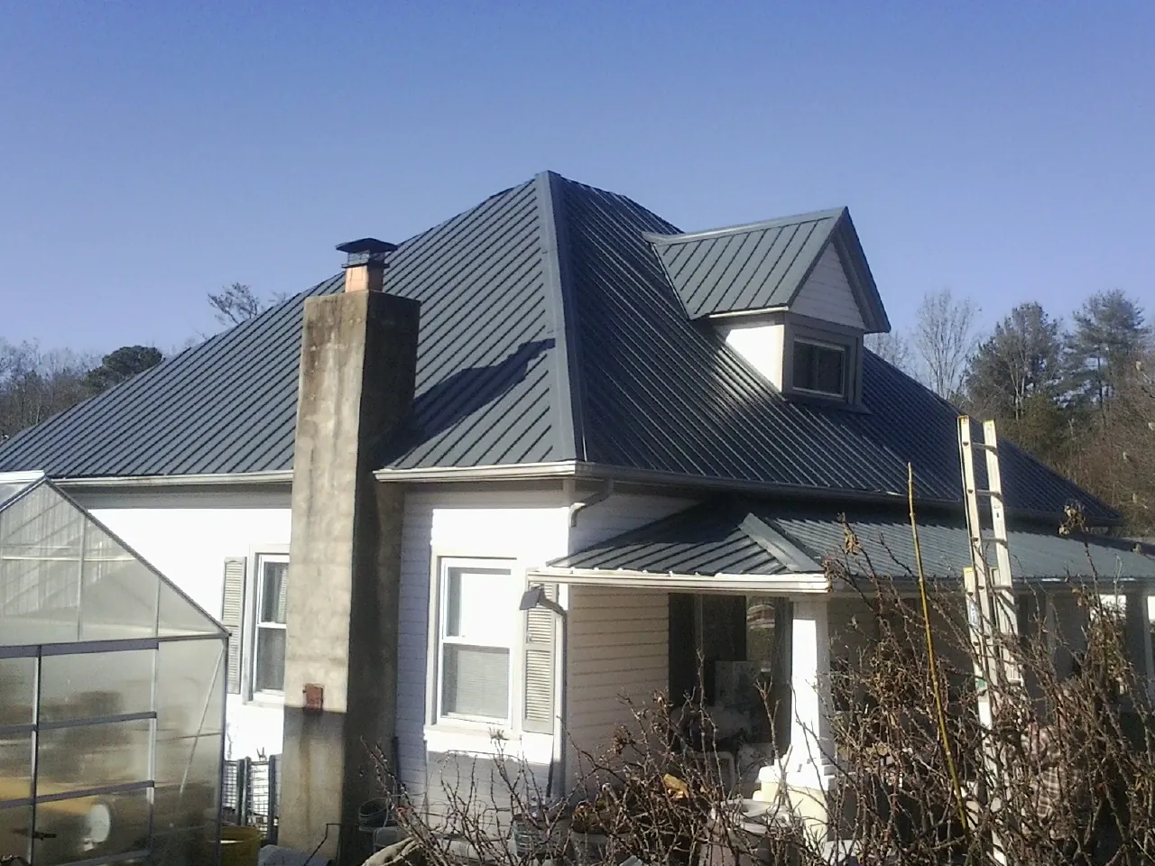 Dark blue standing seam metal roof on a white farmhouse with dormer — Slate & Tile Roof Repair by Roofing Brothers in Wellesley Hills
