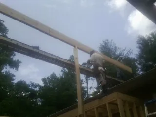 Carpenter setting a ridge beam over a new addition frame — Ice Dam Removal by Roofing Brothers in Wellesley Hills