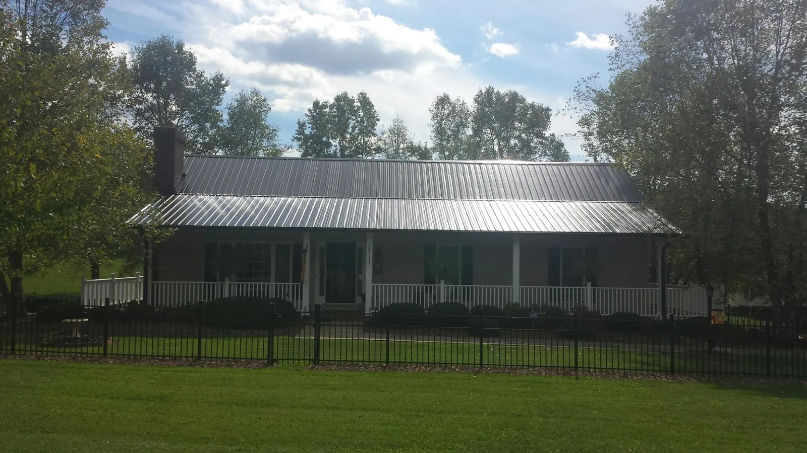 Gray metal roof on a brick ranch with a full width front porch — Gutter Guard Installation work by our crew in Wellesley Hills