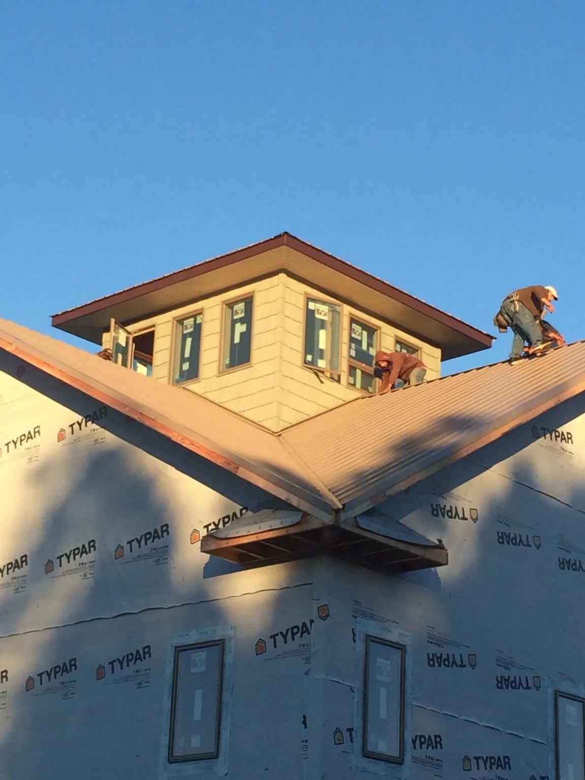 Roofers working around a rooftop cupola on a new metal roof at sunset — Roof Waterproofing in Wellesley Hills by Roofing Brothers